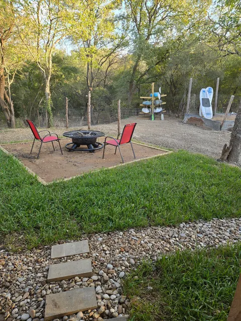 Outdoor chairs and fire pit in the tree-lined Cozy Cabin backyard