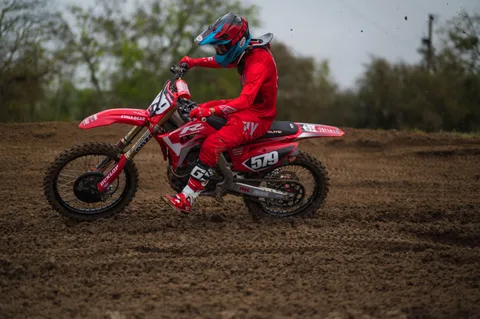 Rider in red gear carving a dirt berm on a red number 579 motocross bike at Creekside MX