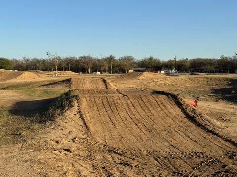 Sunlit dirt jumps and groomed takeoffs across Creekside MX under a clear blue sky
